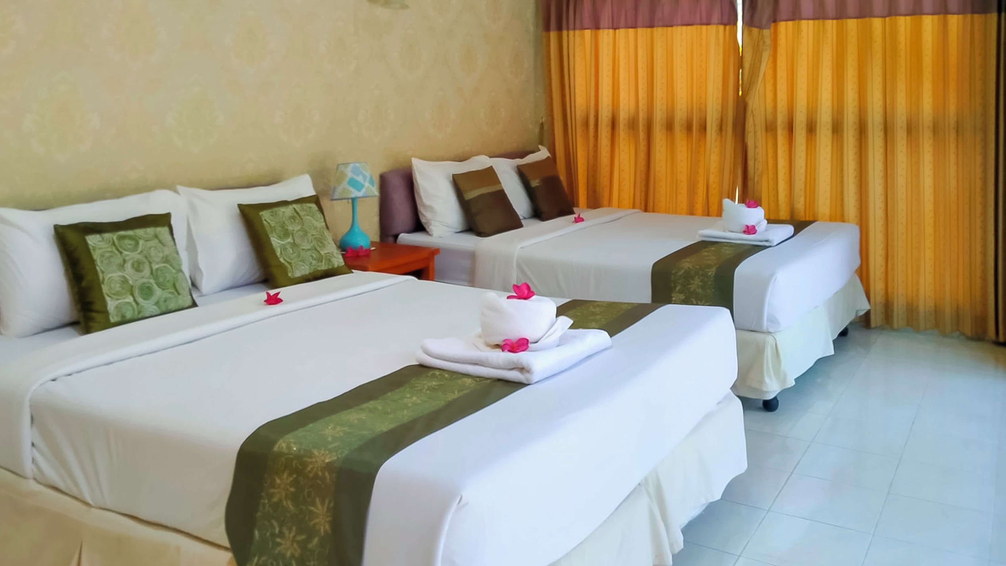 Two beds with white linens, green decorative borders, and pink flowers.