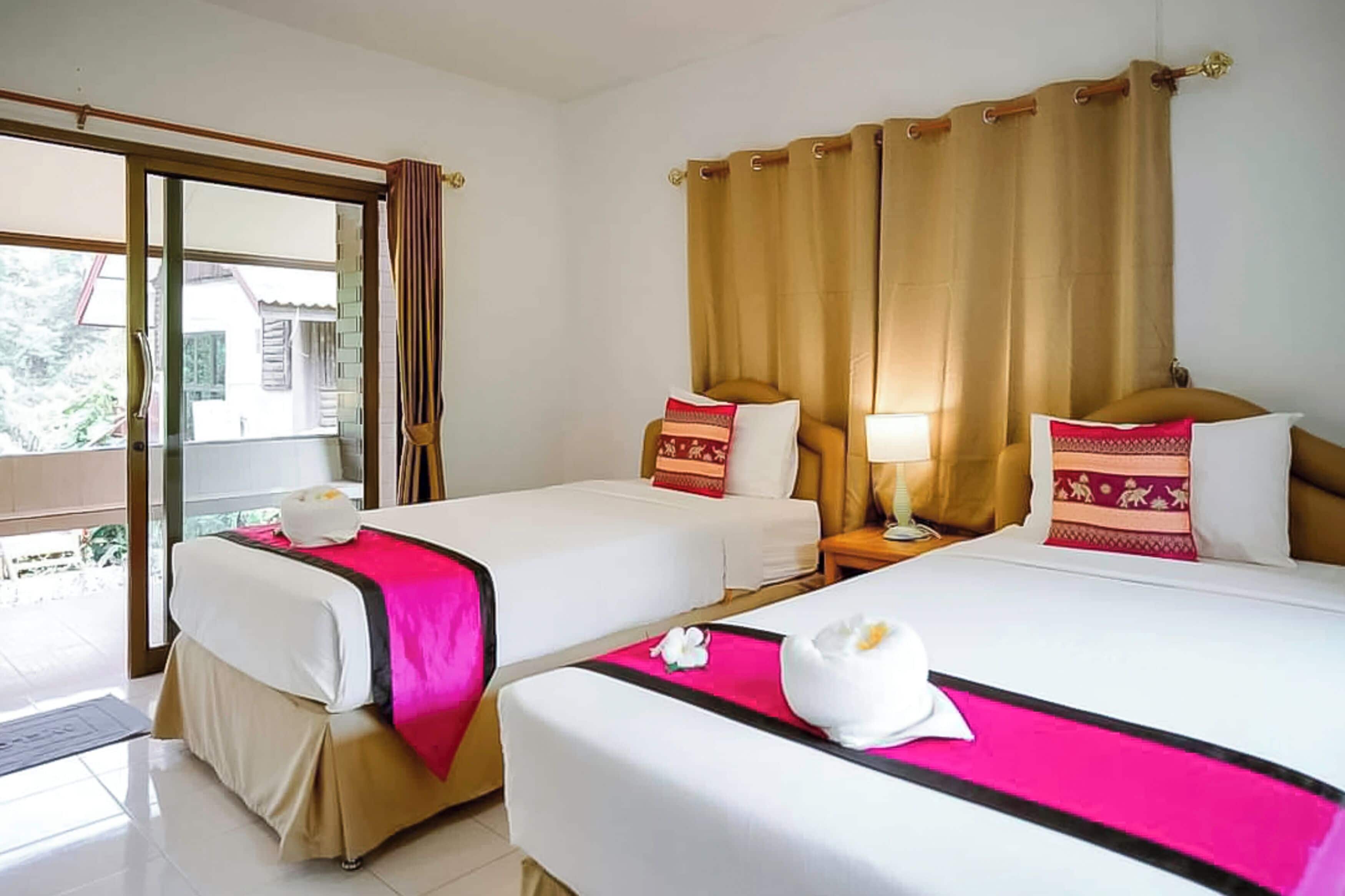 A hotel room with two beds, a sliding glass door to the outside, and a curtain.
