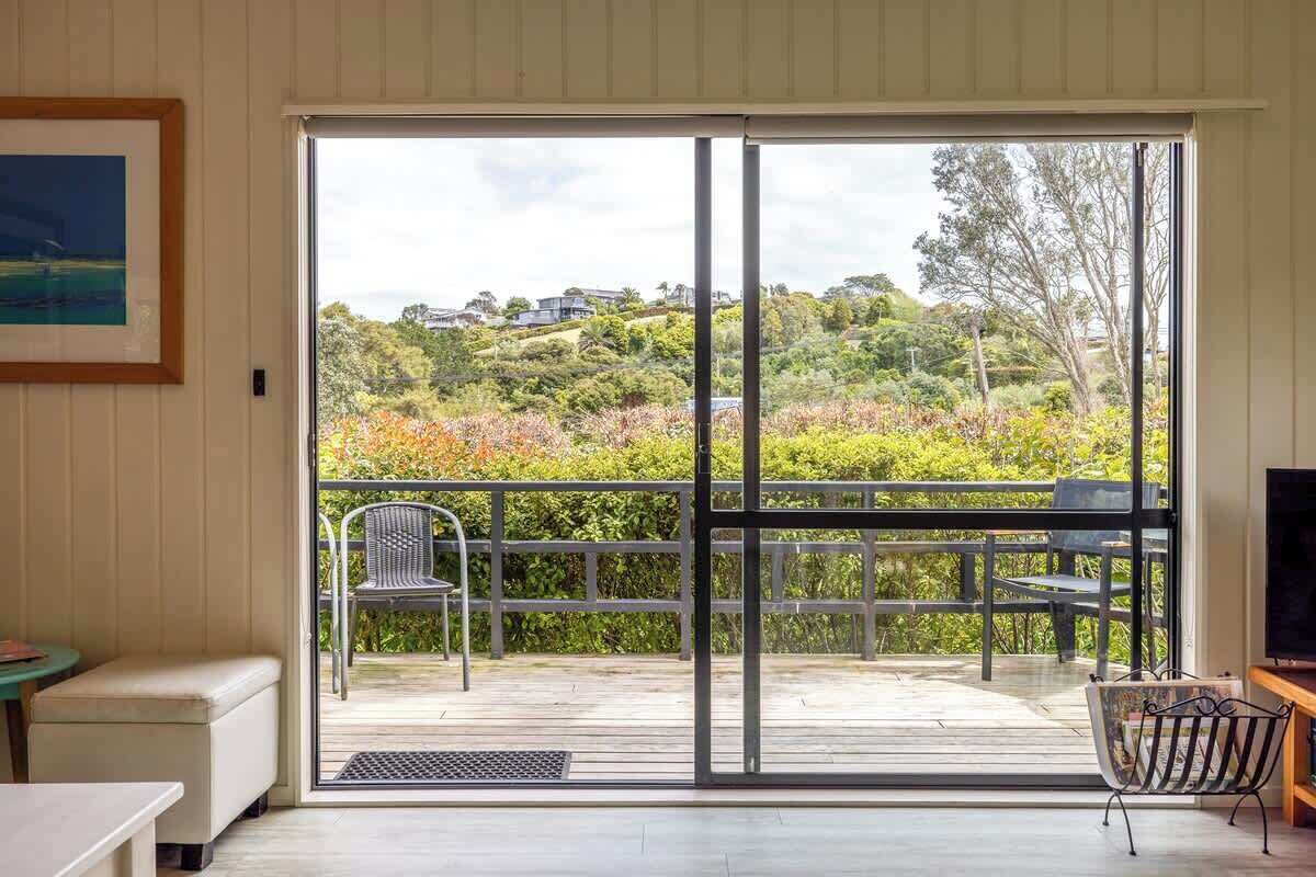 A room with a sliding glass door leading to an outdoor deck with a view of a hilly landscape.