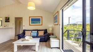 Un salon moderne avec un canapé, une table basse et un balcon aménagé avec des sièges d’extérieur.