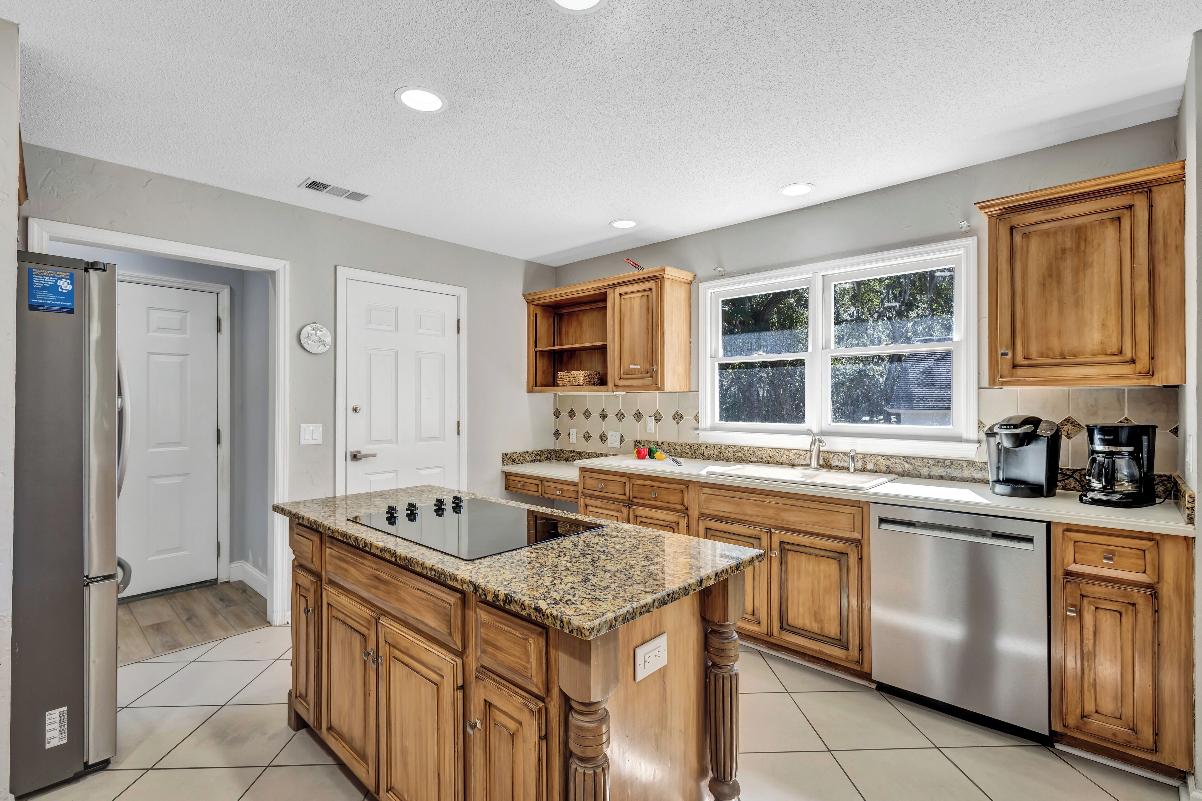 A kitchen with wooden cabinets, a granite countertop, stainless steel appliances, and a window providing natural light.
