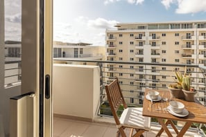 Enjoy a peaceful moment on this balcony with a view, featuring a table for two, a potted plant, and a comfortable chair.