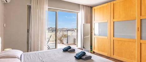 Habitación de hotel con cama, armario, balcón con vistas y aire acondicionado.
