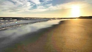 Ein Strand mit ruhiger See und blauem Himmel.