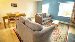 Ein Wohnzimmer mit einer Couch, einem kleinen Tisch und einem Esstisch mit Stühlen.