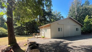 A small, single-story building with a gravel driveway and a wooden deck. - Whispering Pines (Redmond)