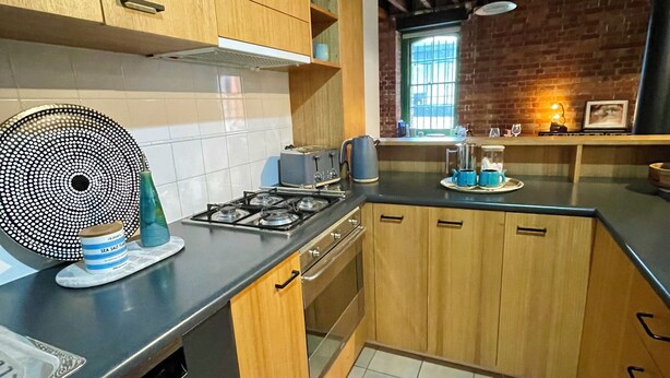 Eine Küche mit Holzausstattung, einem Gasherd, einem Toaster und einem Wasserkocher auf der Arbeitsfläche.