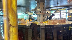 Ein Restaurant mit einer zentralen Bar, einem gemusterten Boden und einem modernen Innendesign.