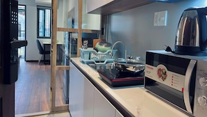 A modern kitchen with a microwave, kettle, and a dish rack. - SenseHome - 5 mins to Bui Vien street  (Ho Chi Minh City)