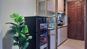 A compact kitchen with a black refrigerator, a wooden door, and a potted plant. - SenseHome - 5 mins to Bui Vien street  (Ho Chi Minh City)