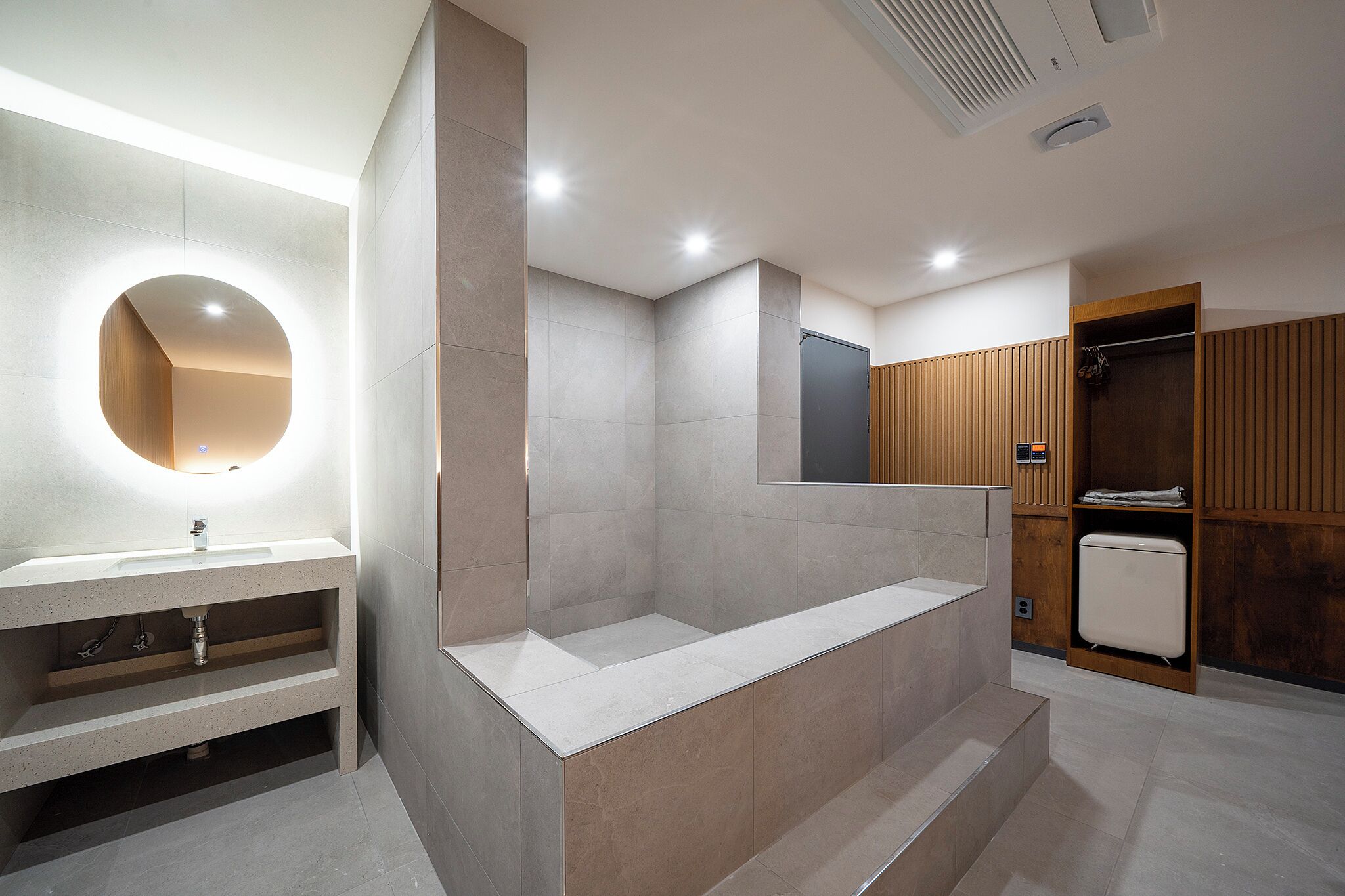 A modern bathroom with a large mirror, a built-in sink, and a shower area.