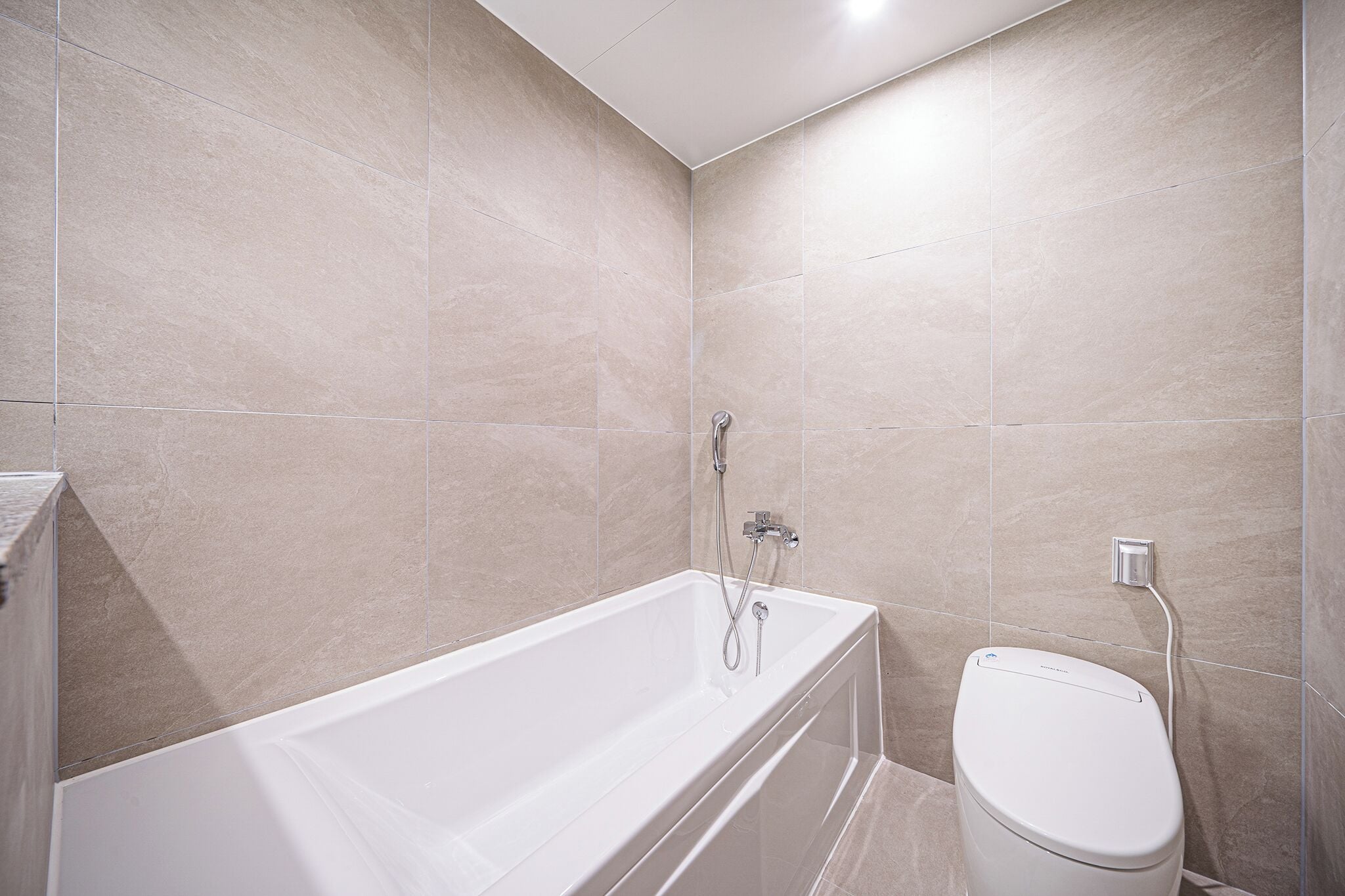 A modern bathroom with a bathtub, toilet, and shower.