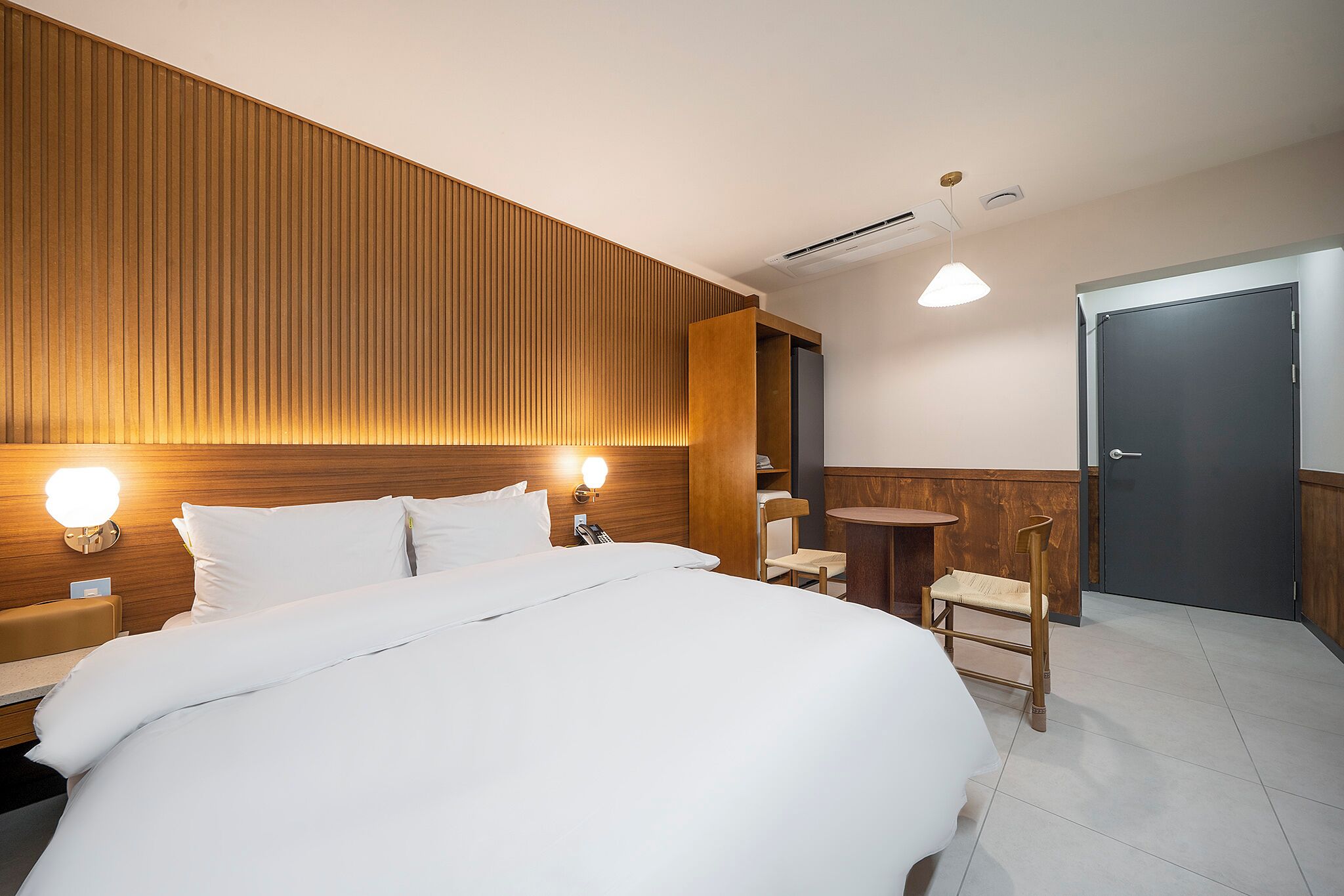 Une chambre d’hôtel avec un grand lit, des tables de chevet, un bureau, une chaise et une petite table.