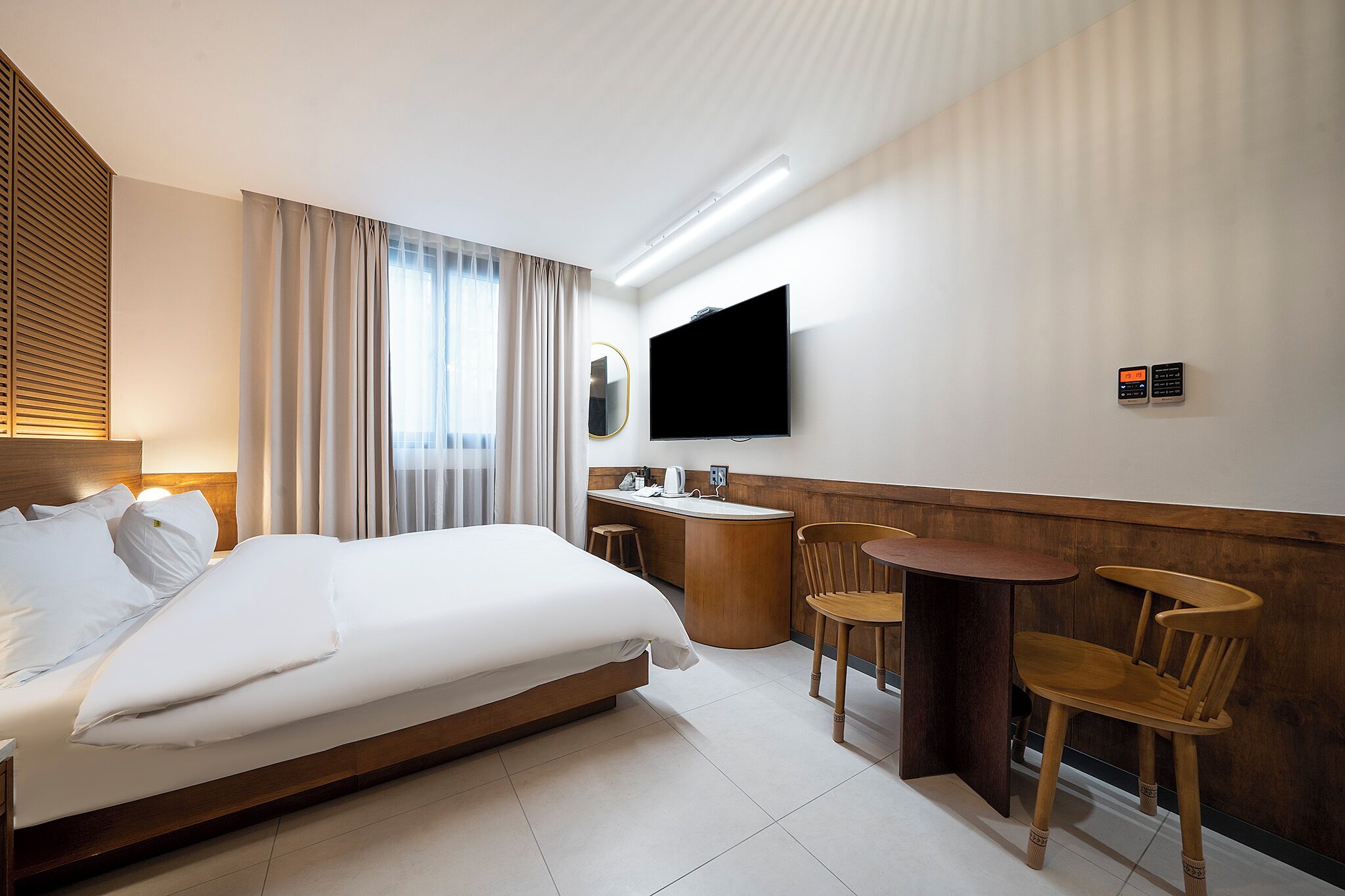 Una habitación de hotel con cama, escritorio, silla, televisor y baño.