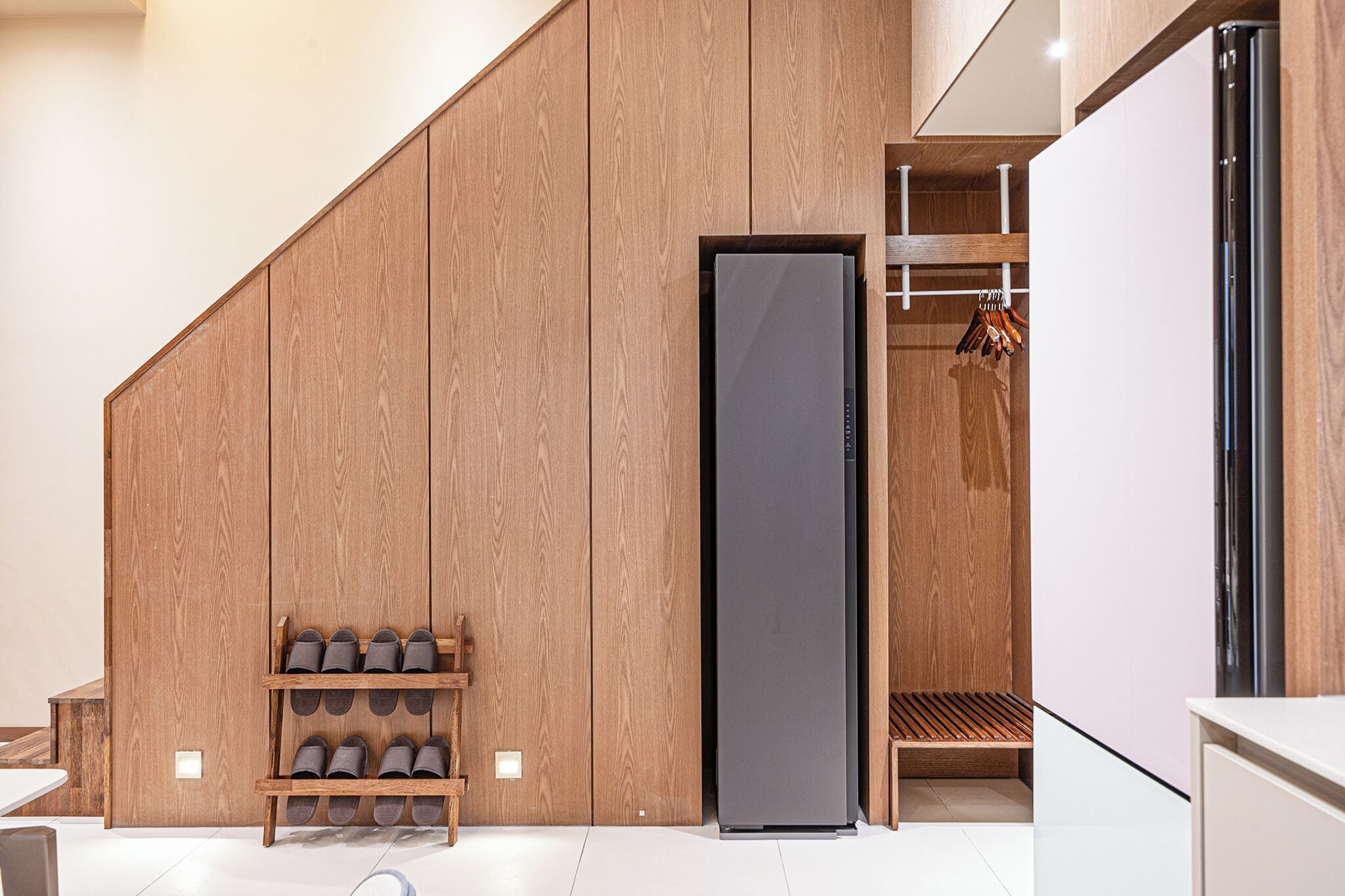 Una cocina moderna con armarios de madera, un refrigerador integrado y un zapatero.