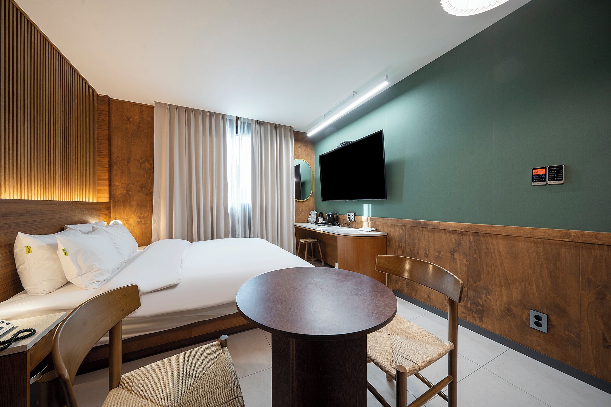 Une chambre d’hôtel équipée d’un lit, d’un bureau, d’une chaise, d’une table ronde, d’un téléviseur et d’un miroir.