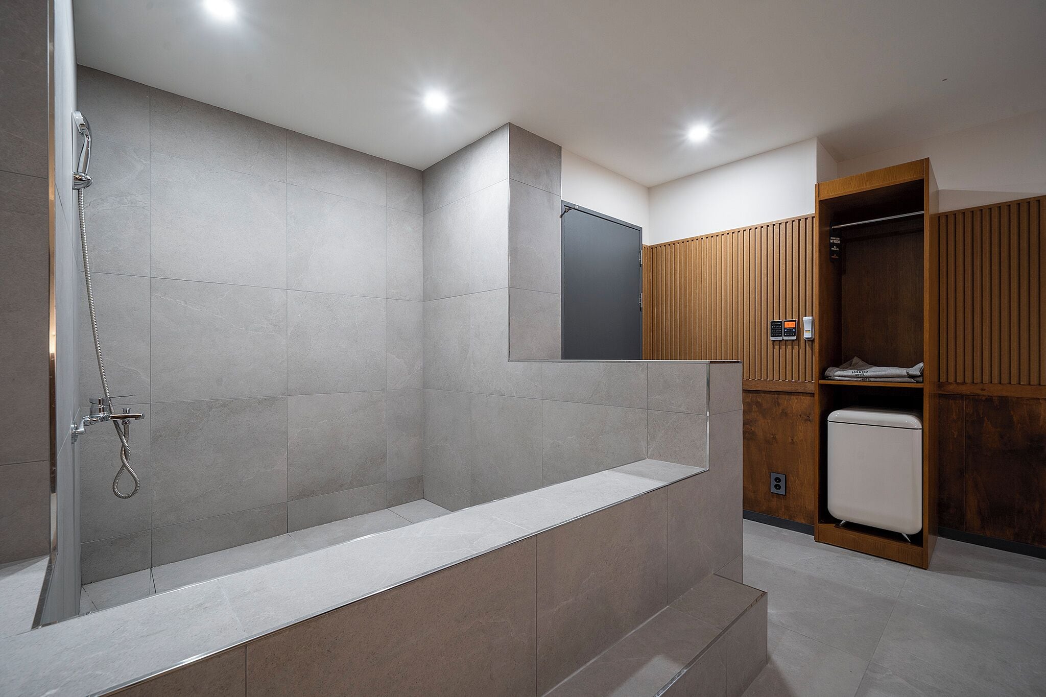 Un baño moderno con ducha a nivel, un banco integrado y un armario de madera.