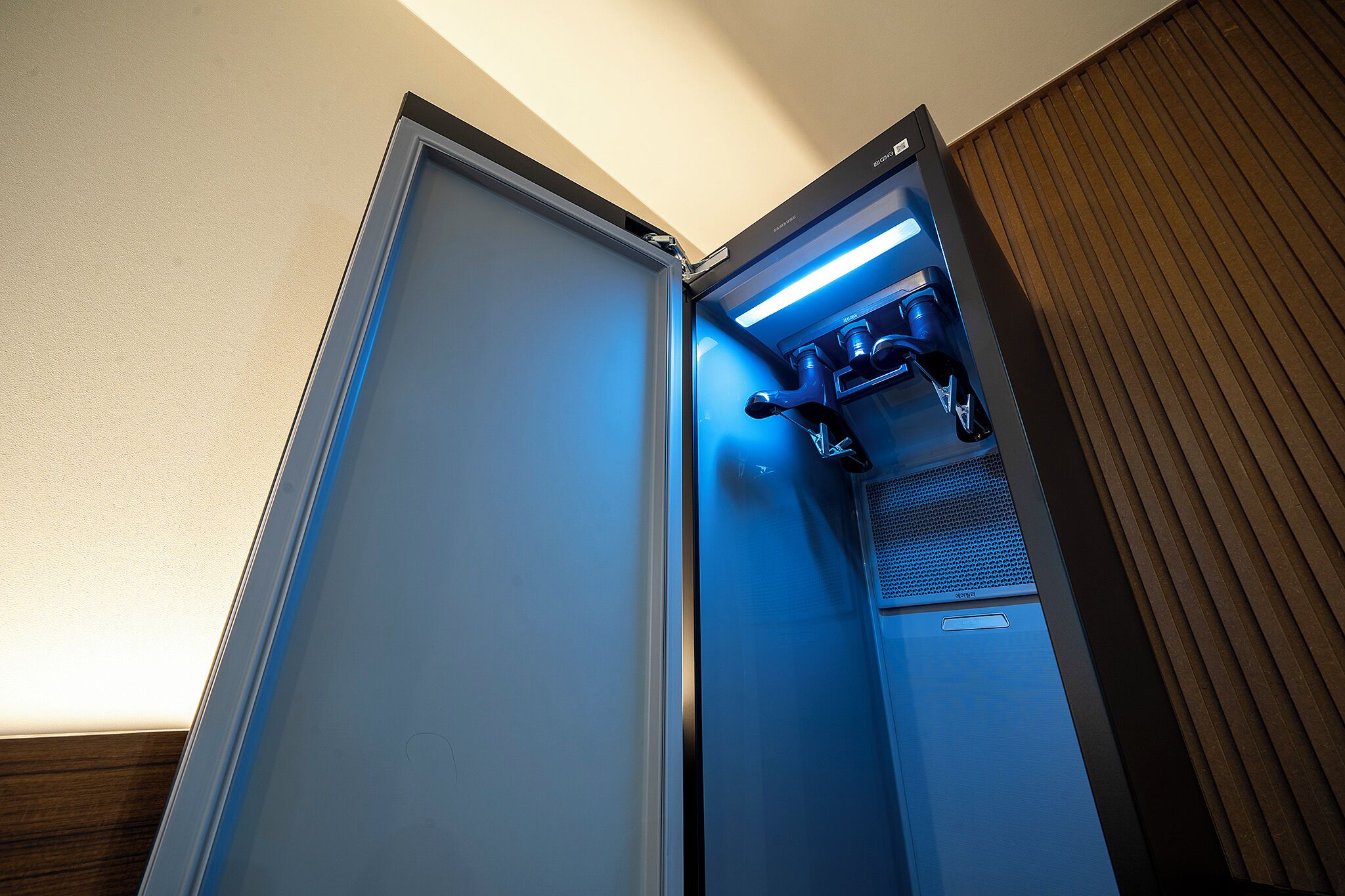 A hotel room with a minibar, a built-in coffee machine, and a wooden panel wall.