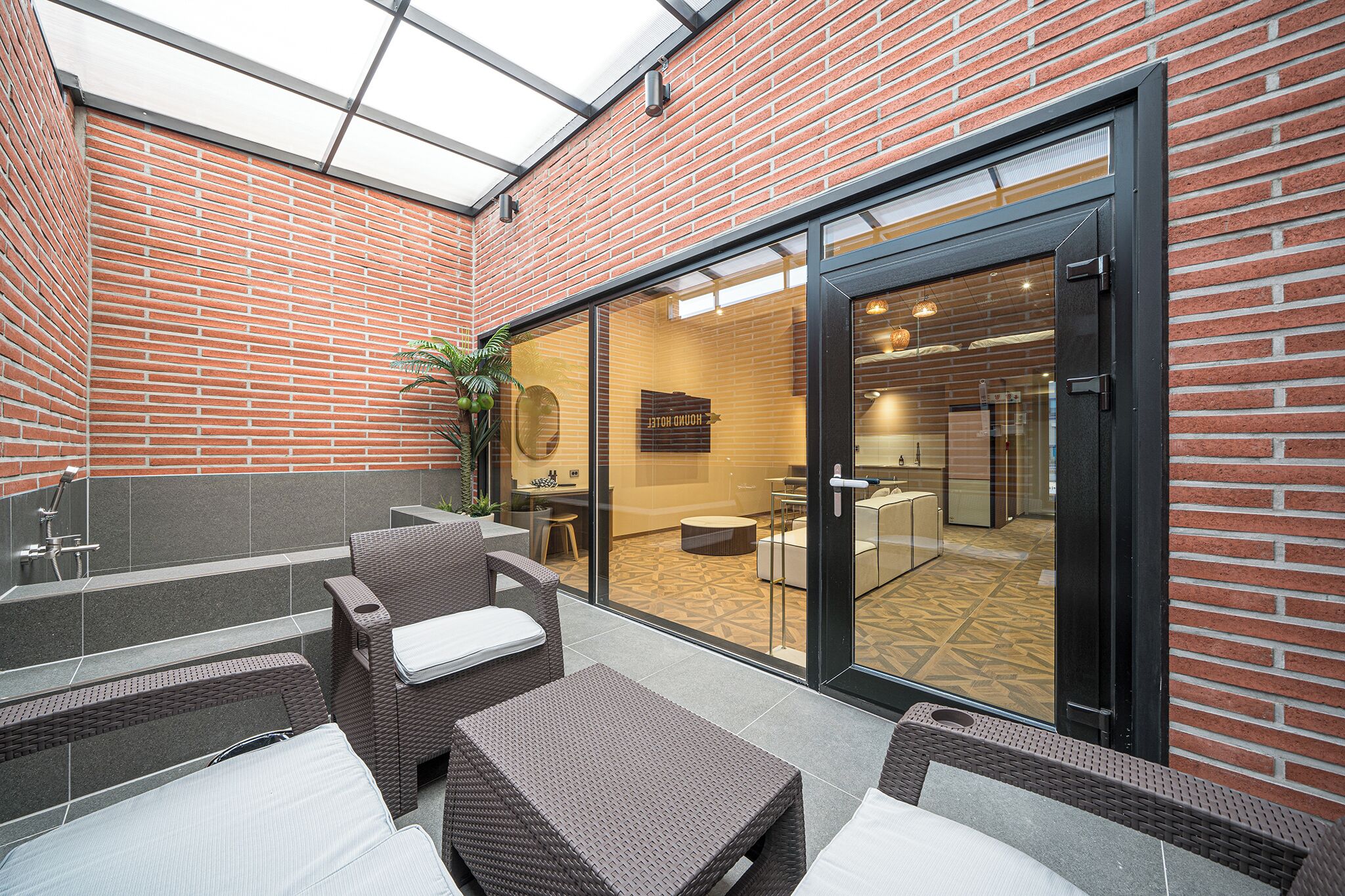 A modern outdoor patio with wicker furniture and a glass door leading to an interior space.