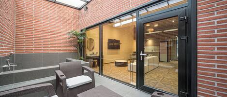A modern outdoor patio with wicker furniture and a glass door leading to an interior space.
