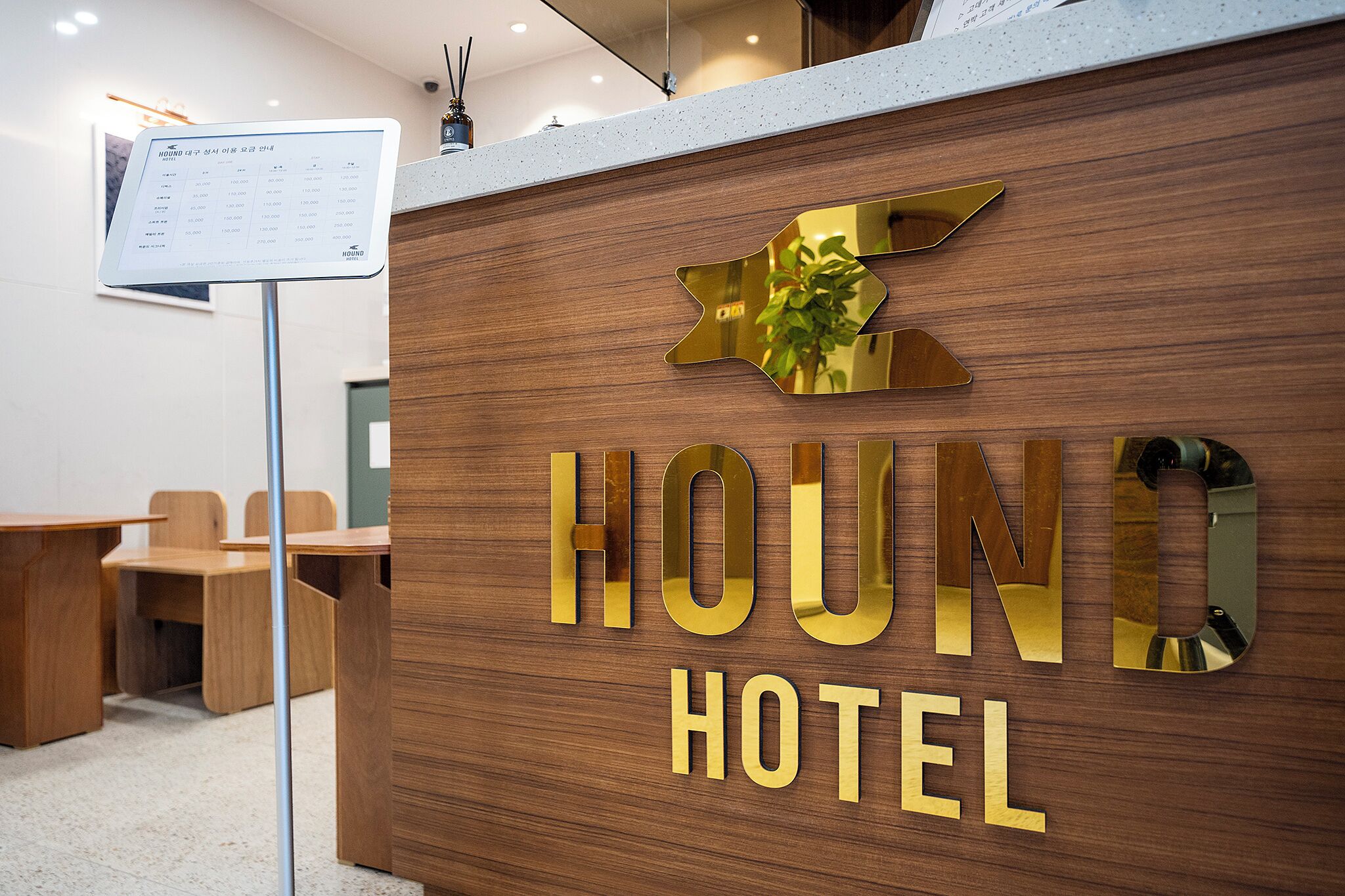 A reception desk at Hound Hotel with a wooden finish and a signboard.