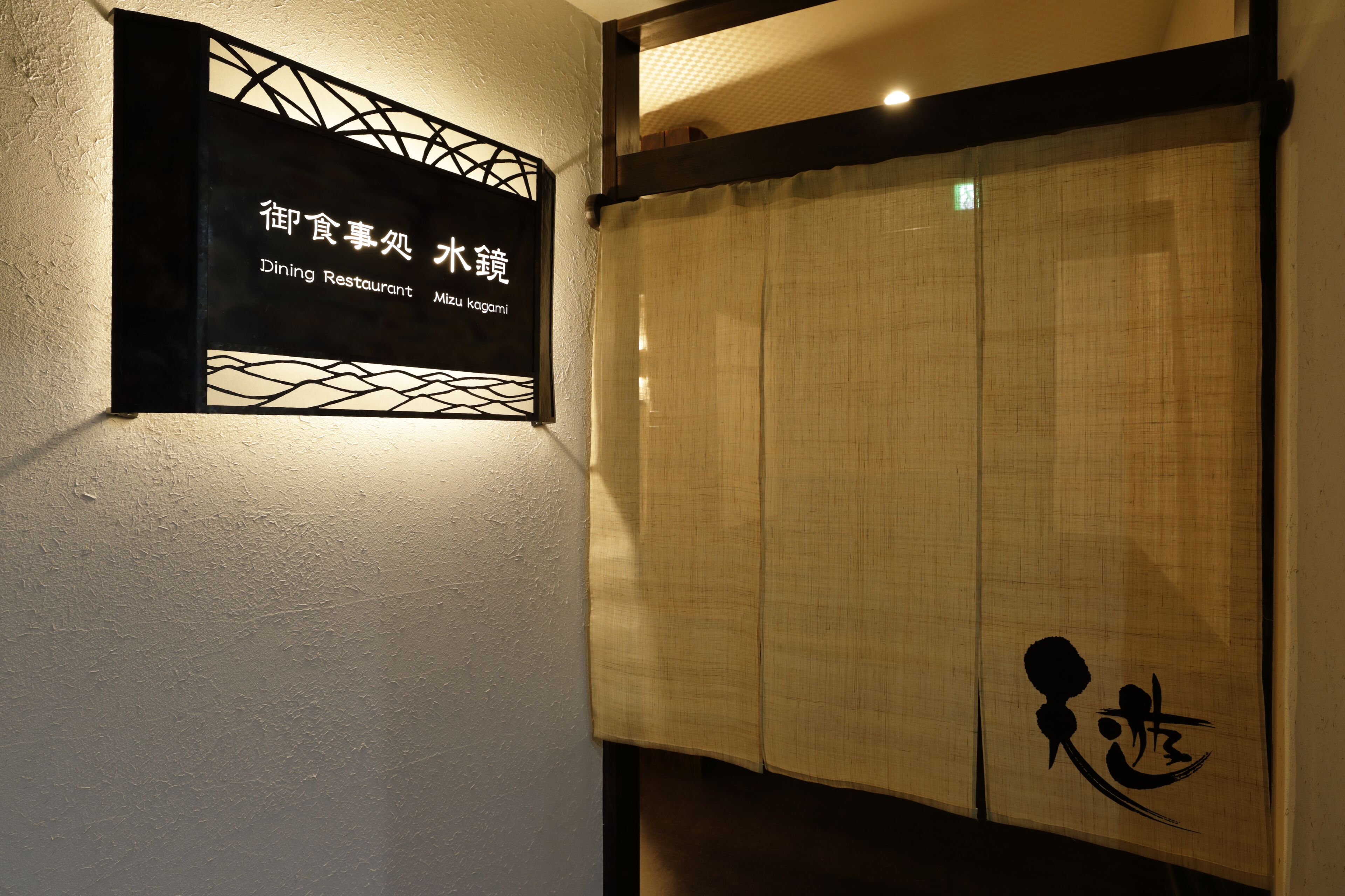 Letrero de restaurante con caracteres japoneses y una puerta corredera tradicional con un emblema decorativo.