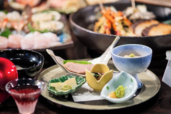 Diverse gerechten op een tafel, waaronder sushi, sashimi en andere Aziatische keuken.