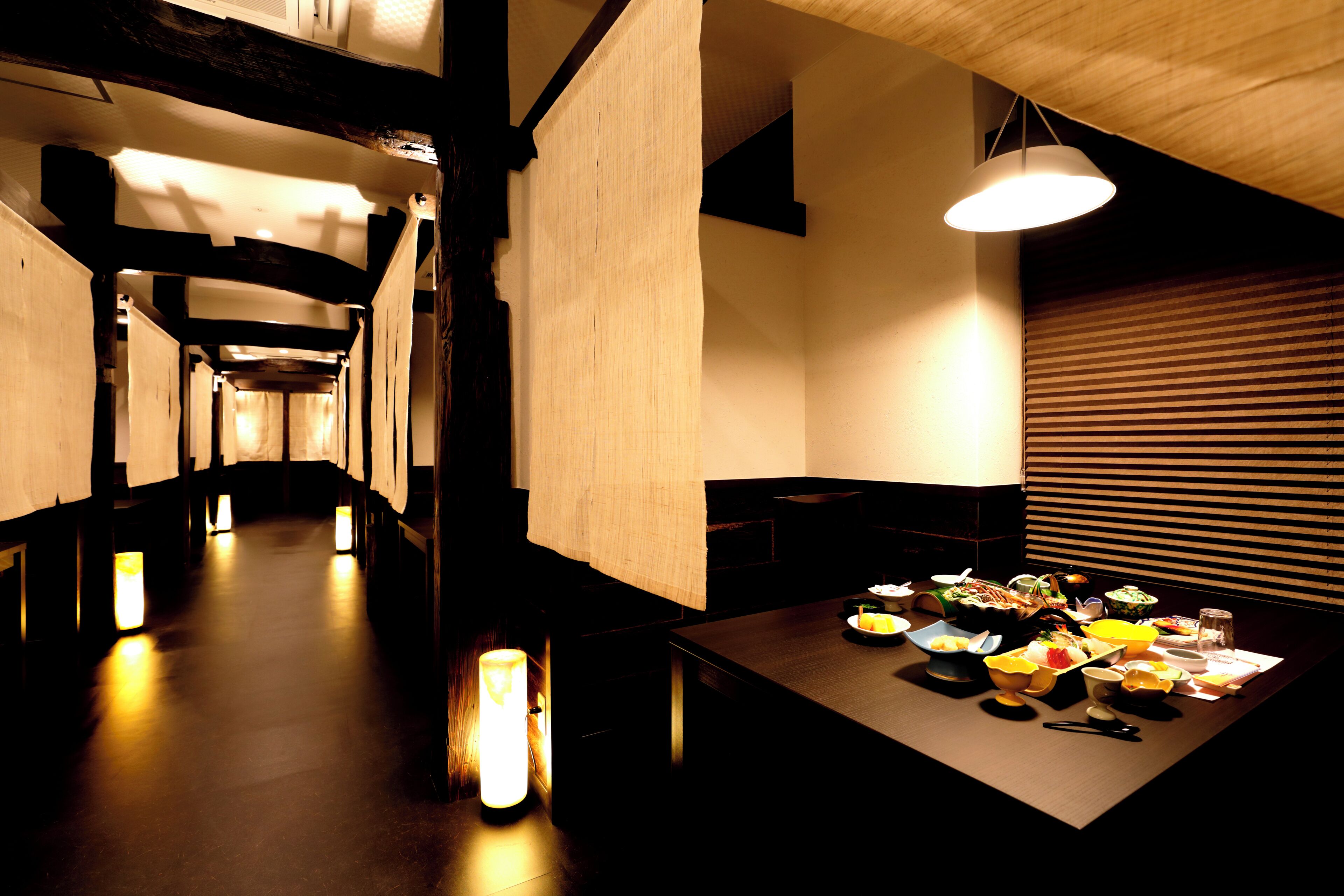 A dimly lit corridor with wooden beams and a table set with various dishes and a candle.