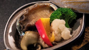 Gros plan d’un plat de fruits de mer composé d’une noix de Saint-Jacques, de brocolis, de chou-fleur et d’une tranche de poivron rouge.