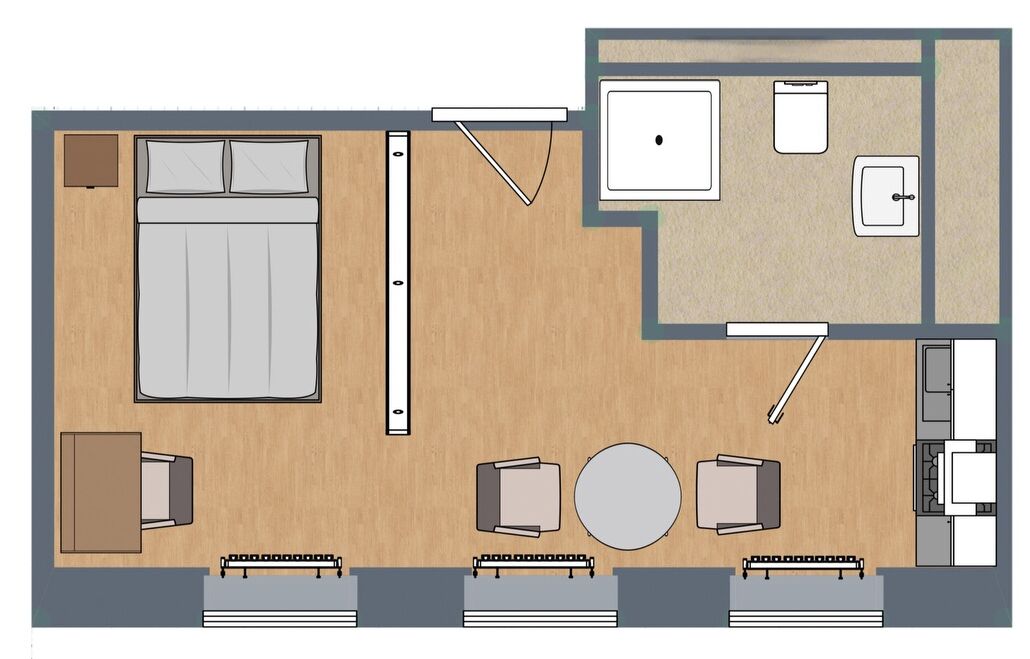 Ein Hotelzimmer mit Bett, Nachttisch, zwei Stühlen, einem kleinen Tisch, einer Couch, einem runden Tisch, einem Schreibtisch, einem Sessel, einem kleinen Schrank und einem Fenster.