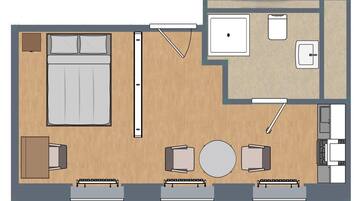Ein Hotelzimmer mit Bett, Nachttisch, zwei Stühlen, einem kleinen Tisch, einer Couch, einem runden Tisch, einem Schreibtisch, einem Sessel, einem kleinen Schrank und einem Fenster.
