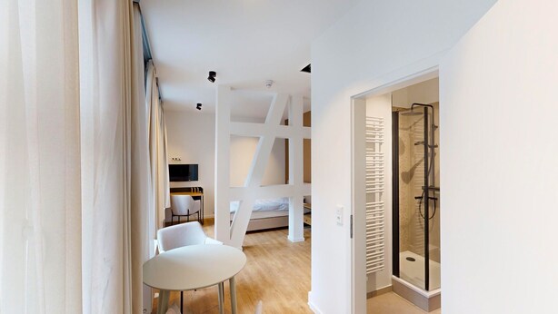 Une chambre moderne comprenant un lit, un bureau, une chaise et un espace douche.