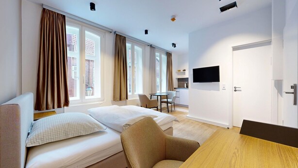 Una habitación de hotel moderna con cama, escritorio, silla y televisor.