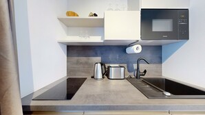 Una cocina moderna con microondas integrado, hervidor, tostadora y fregadero.