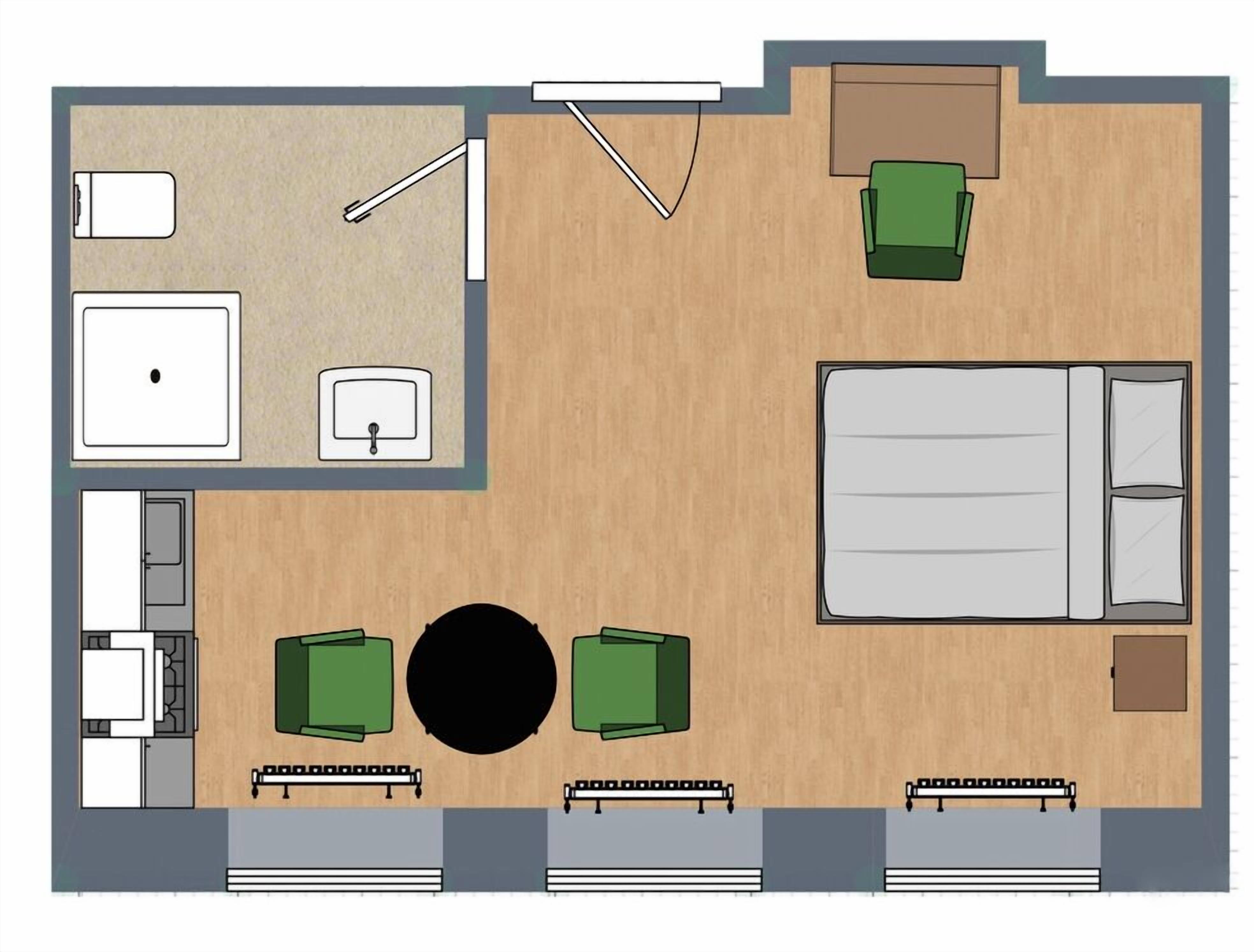 Ein Hotelzimmer mit Bett, zwei grünen Sesseln, einem kleinen Tisch, einem Schreibtisch, einem Stuhl, einem Kleiderschrank und einem Badezimmer.