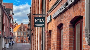 Et gadesyn med en markant bygning med skiltet "Boardinghouse Lüneburg" og et skilt der angiver "Nr. 8A".