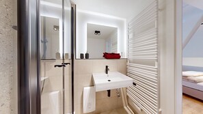Bathroom features a glass-enclosed shower, sink, and towel rack, with a large mirror above the sink.
