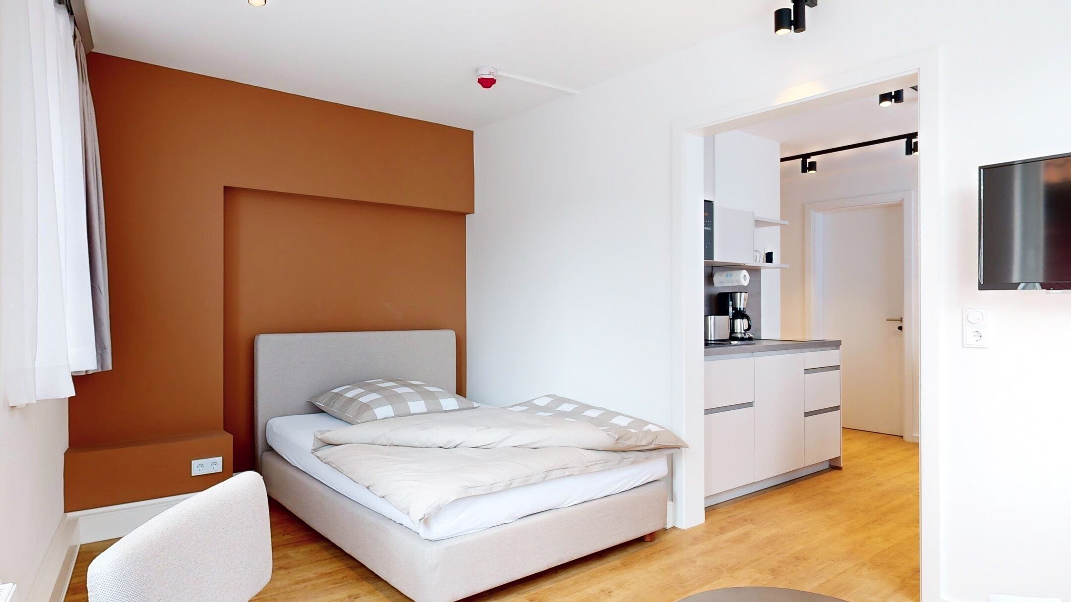 Ein modernes Schlafzimmer mit Bett, Schreibtisch und einer Küchenzeile.