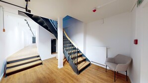 A modern interior with a wooden staircase, a chair, and a blue accent wall. - Apartment 9 | Boardinghouse Lüneburg No8A (Lüneburg)