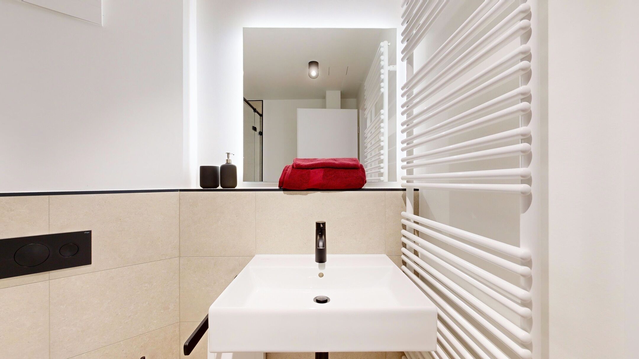A modern bathroom with a white sink, a mirror, and a towel rack.