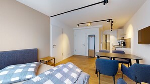 Een moderne, compacte kamer met een bed, een klein tafeltje en een zithoek.