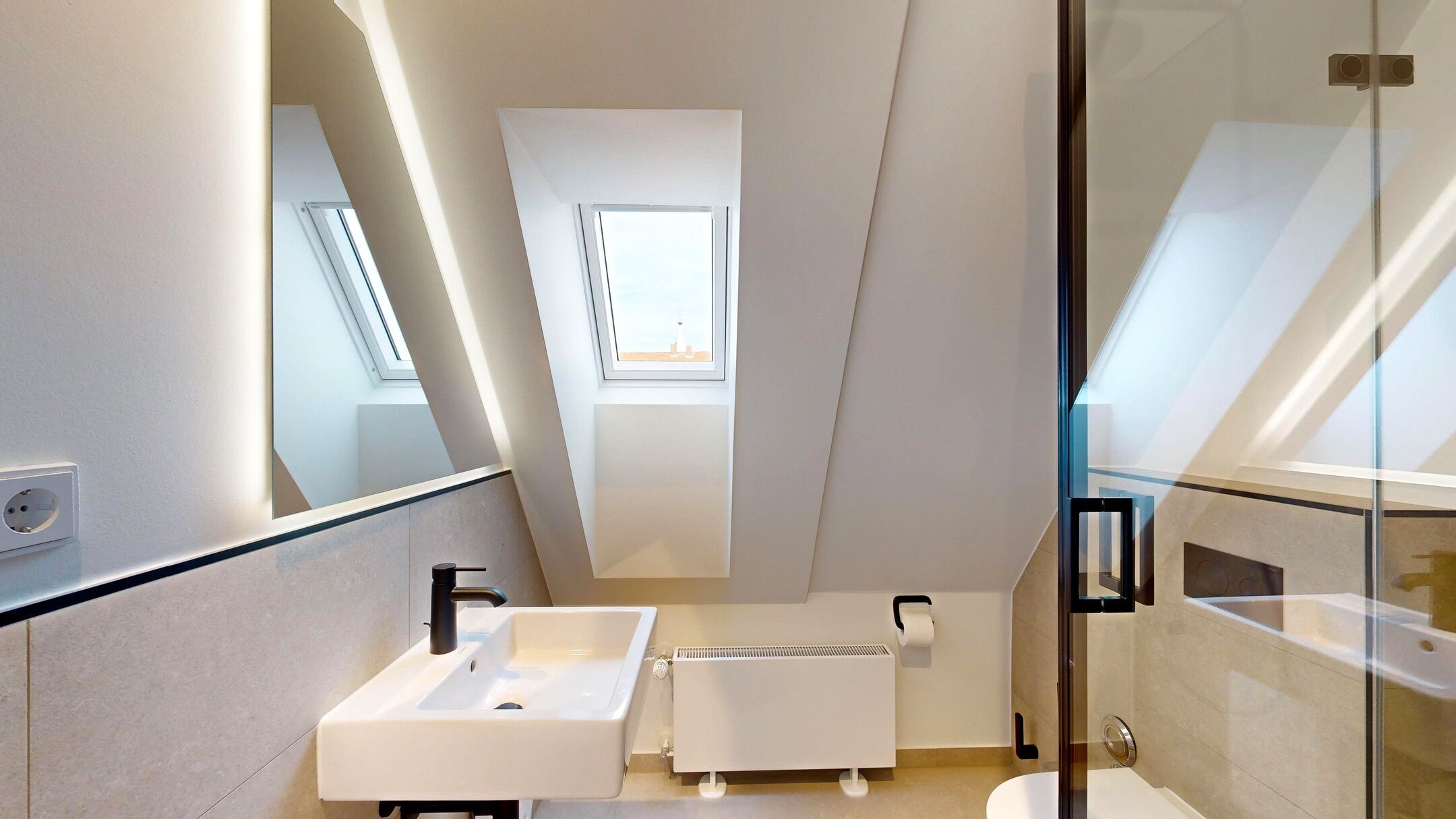 Un baño moderno con tragaluz, un lavabo blanco y una cabina de ducha de vidrio.