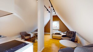 Una habitación moderna y compacta con kitchenette, zona de comedor y cama.