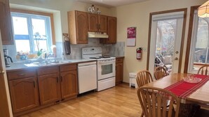 A kitchen with wooden cabinets, a stove, and a dining table with chairs. - Bright, spacious 4 bedroom home. (Cochrane)