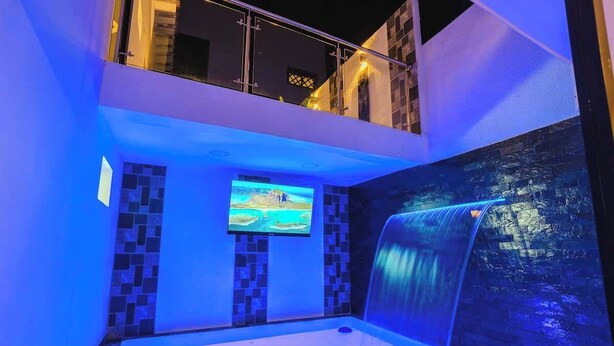 Un área de spa con un jacuzzi, una cascada y una pantalla de televisión.