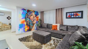 Una sala de estar moderna con un sofá grande, una mesita de centro y un mural colorido en la pared.