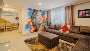 Una sala de estar moderna con un gran mural colorido, un conjunto de sofás y una zona de comedor.