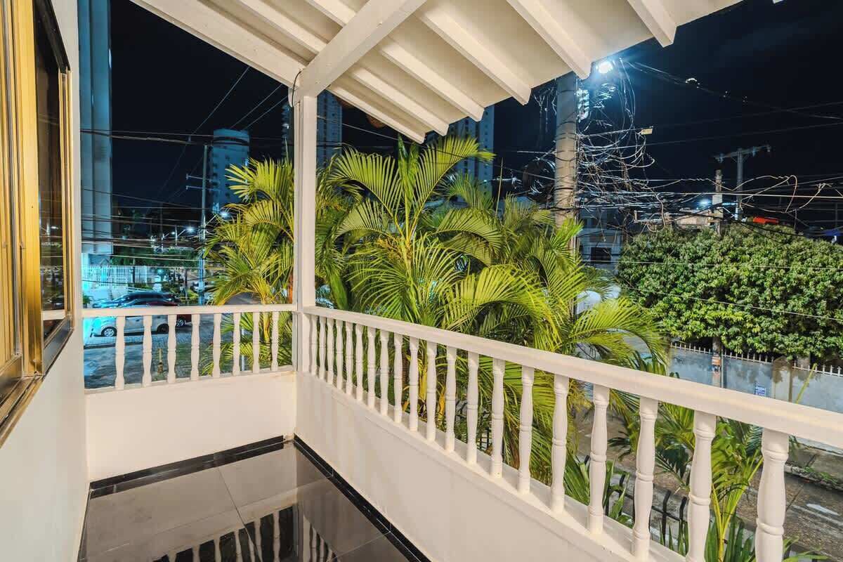 A balcony with a white railing, surrounded by lush green plants.