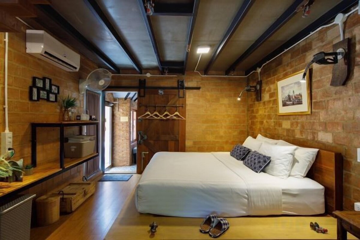 Un dormitorio con una cama, un aparador de madera, un calentador de pared y una pared de ladrillo.