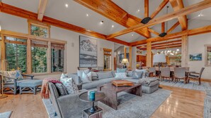 A spacious living room with a large sectional sofa, a coffee table, and a dining area with wooden chairs. - Northstar Ski-In/Ski-Out with Hot Tub & Views (Northstar)